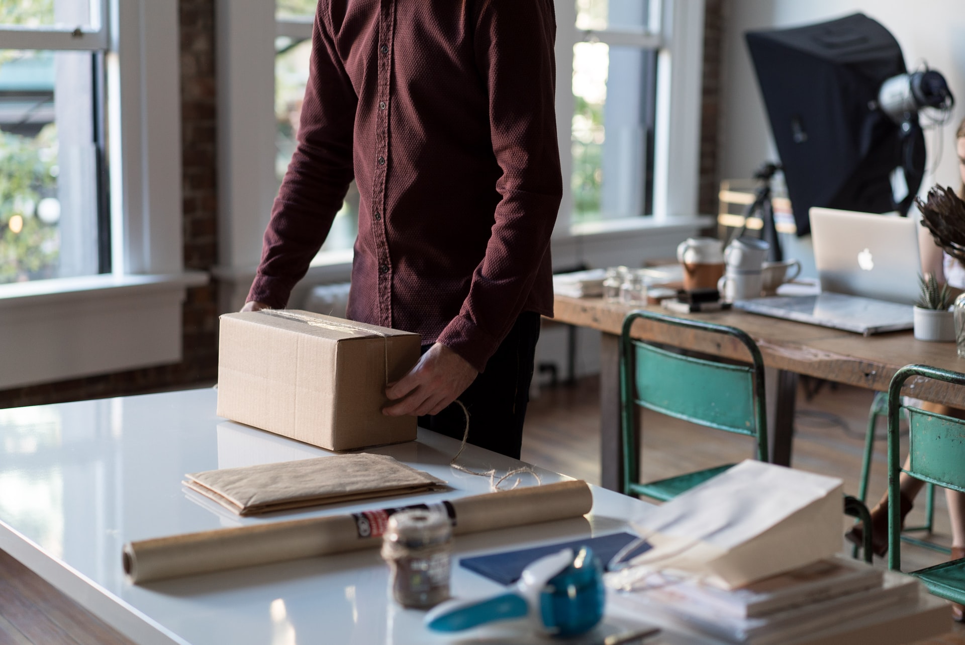 Person wrapping cardboard box on table