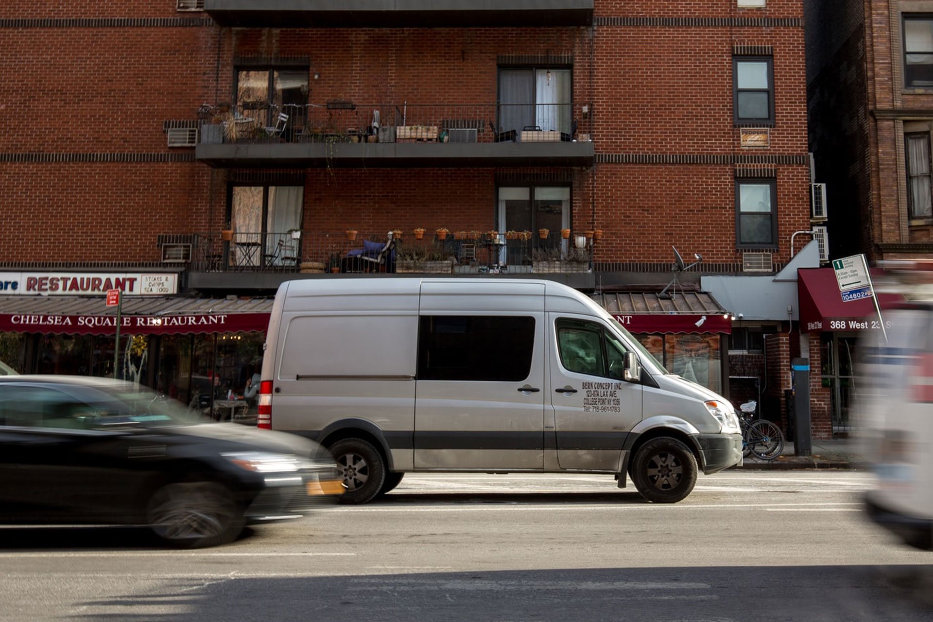 Grey company work van parked on a busy road